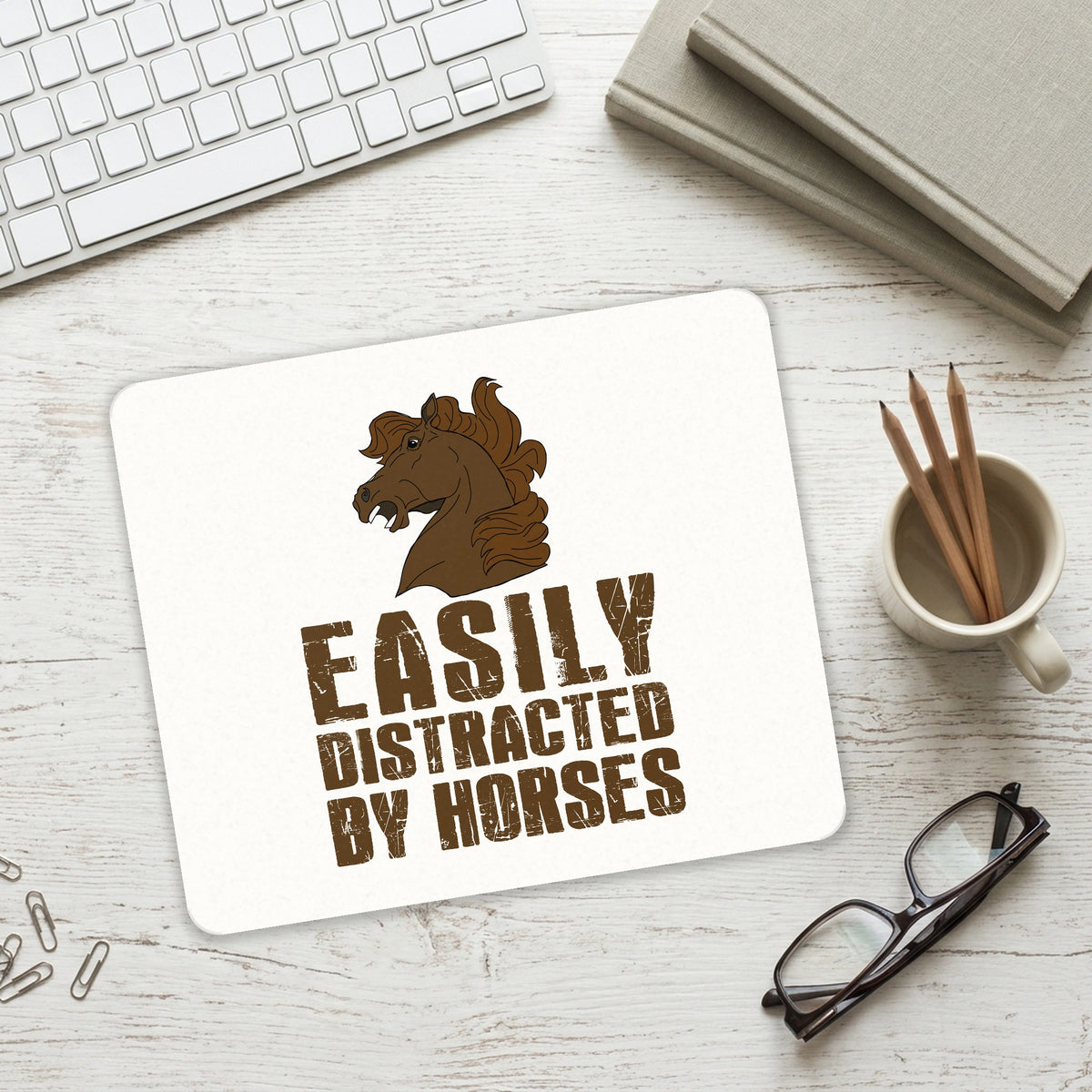 Easily Distracted By Horses mouse pad on a desk with a keyboard
