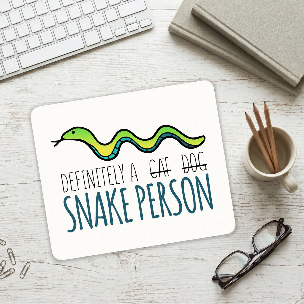 Definitely a Snake Person mouse pad on a desk with a keyboard