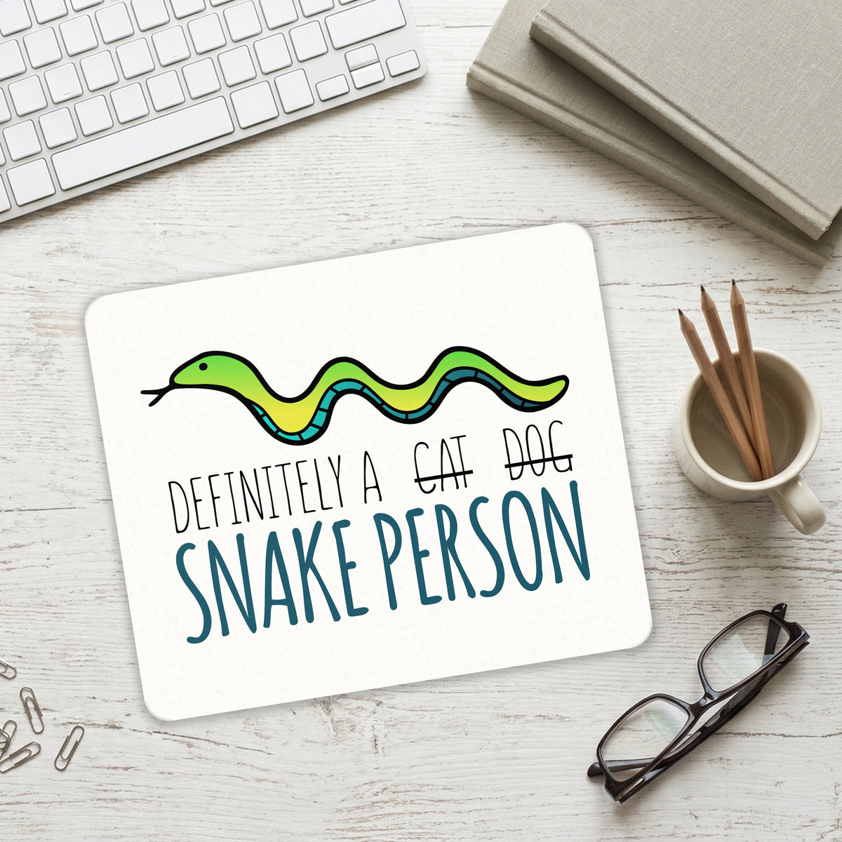 Definitely a Snake Person mouse pad on a desk with a keyboard