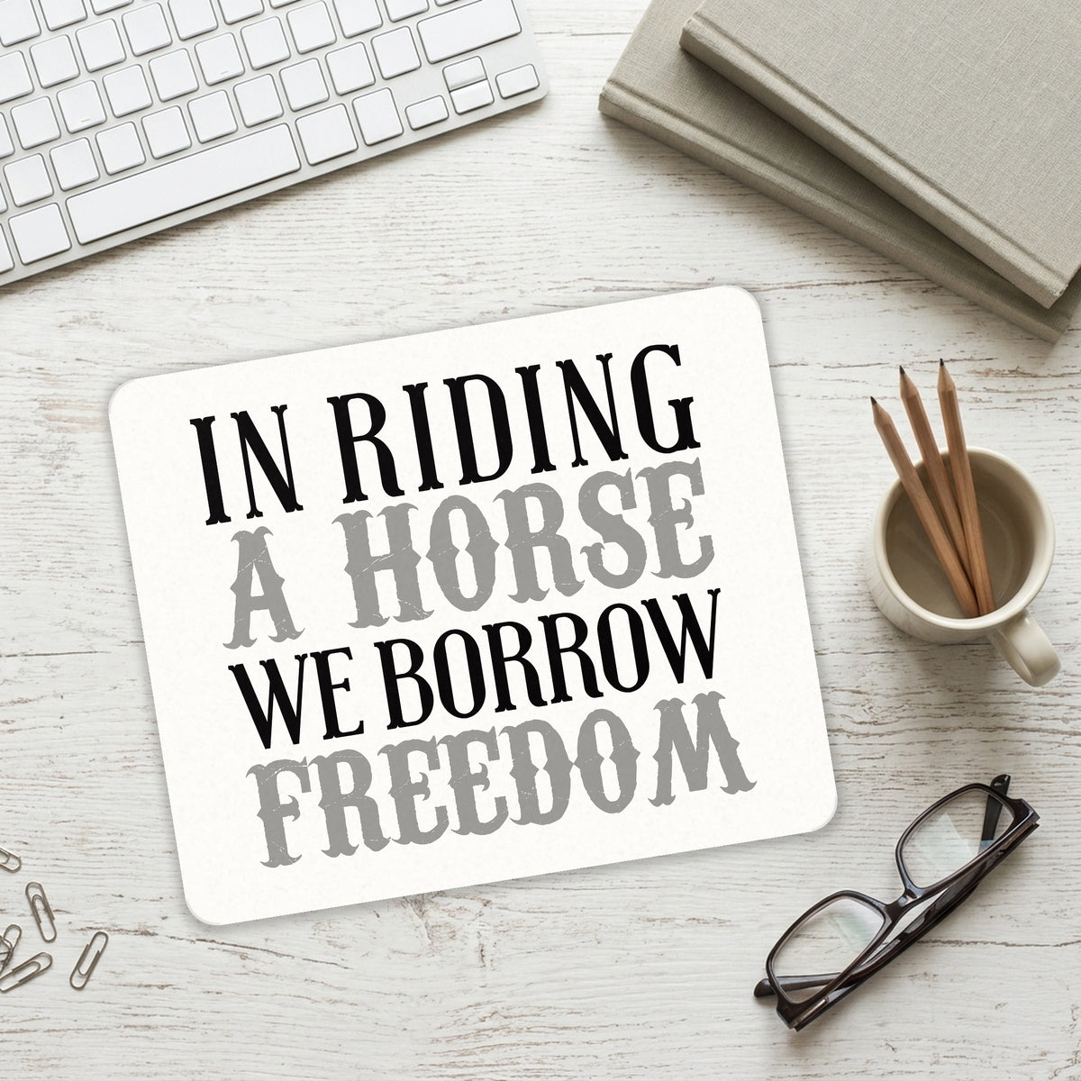 In Riding a Horse, We Borrow Freedom mouse pad on a desk with a keyboard