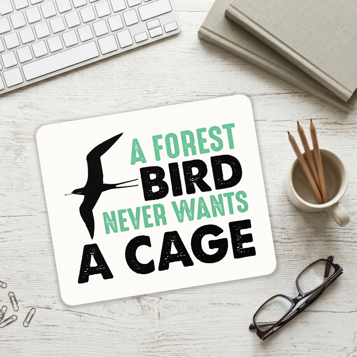 A Forest Bird Never Wants a Cage mouse pad on a desk with a keyboard