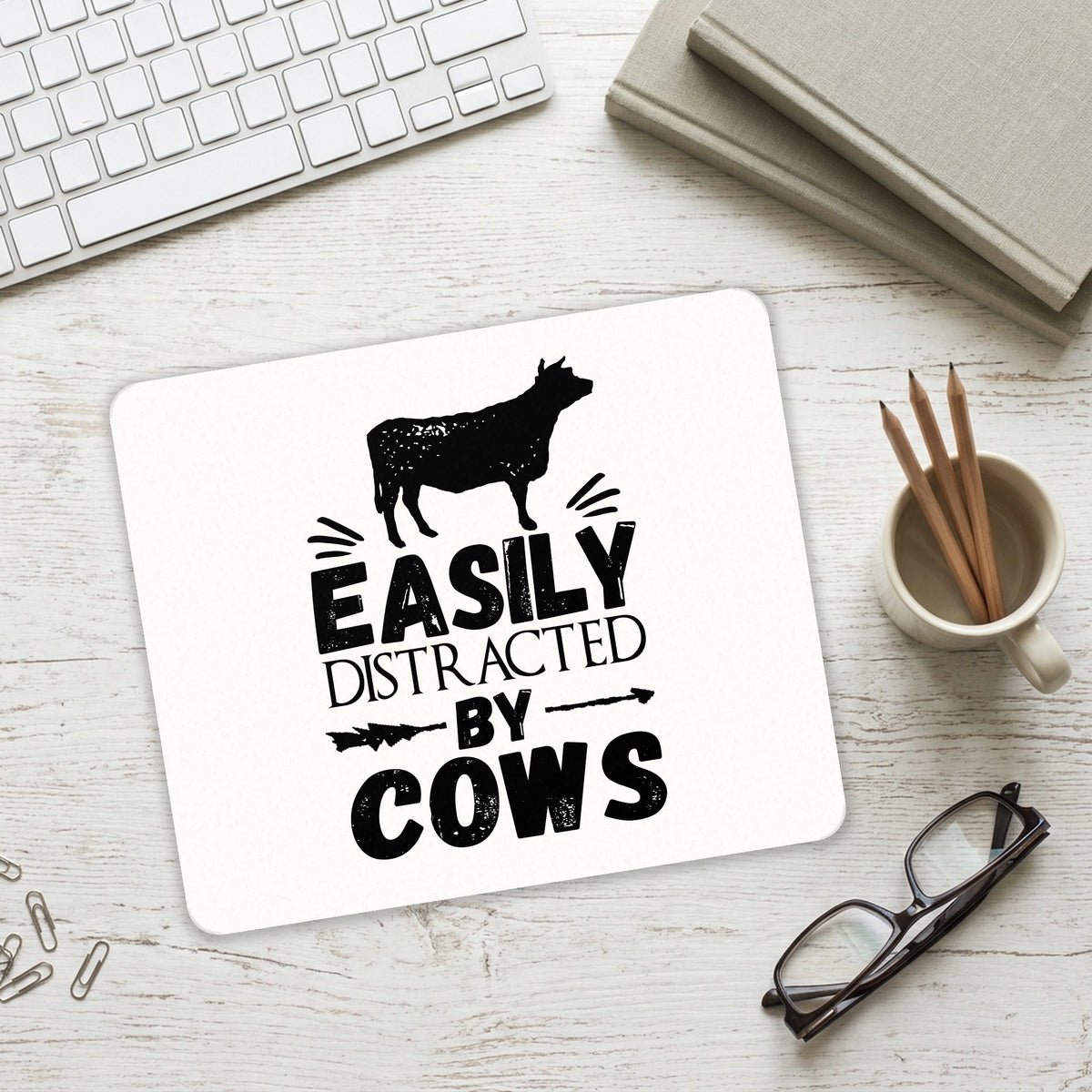 Easily Distracted By Cows mouse pad on a desk with a keyboard