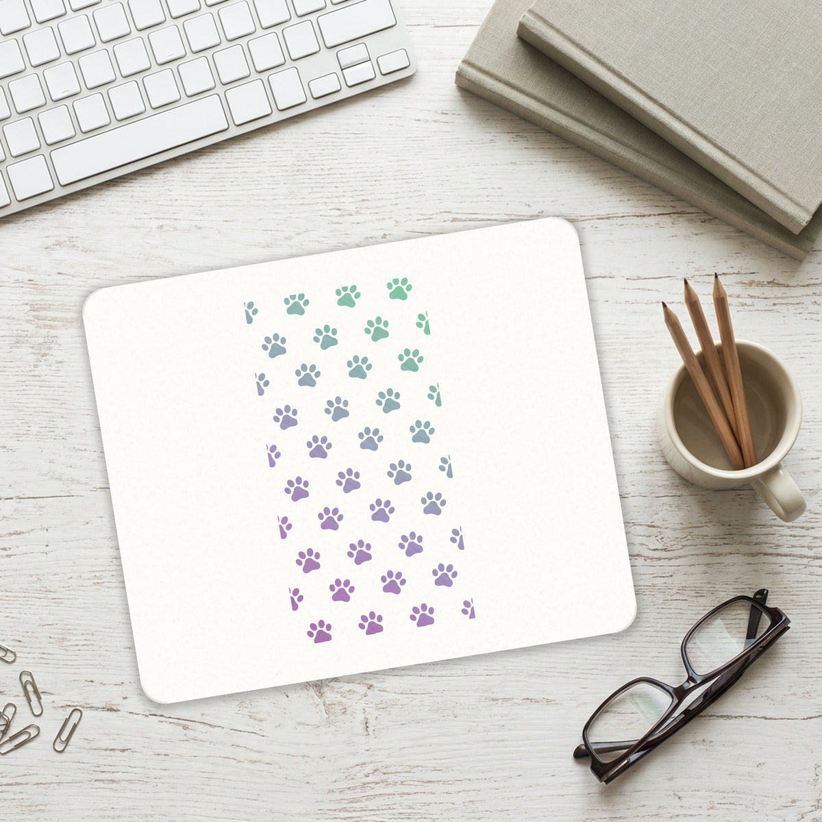 Gradient Pawprints - Purple to Green mouse pad on a desk with a keyboard
