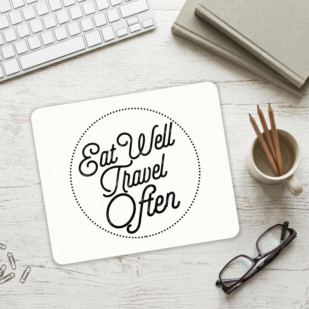 Eat Well, Travel Often mouse pad on a desk with a keyboard