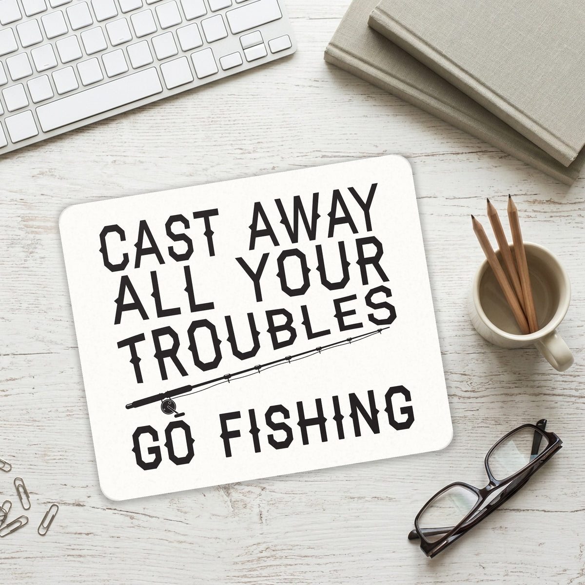 Cast Away All Your Troubles Go Fishing mouse pad on a desk with a keyboard