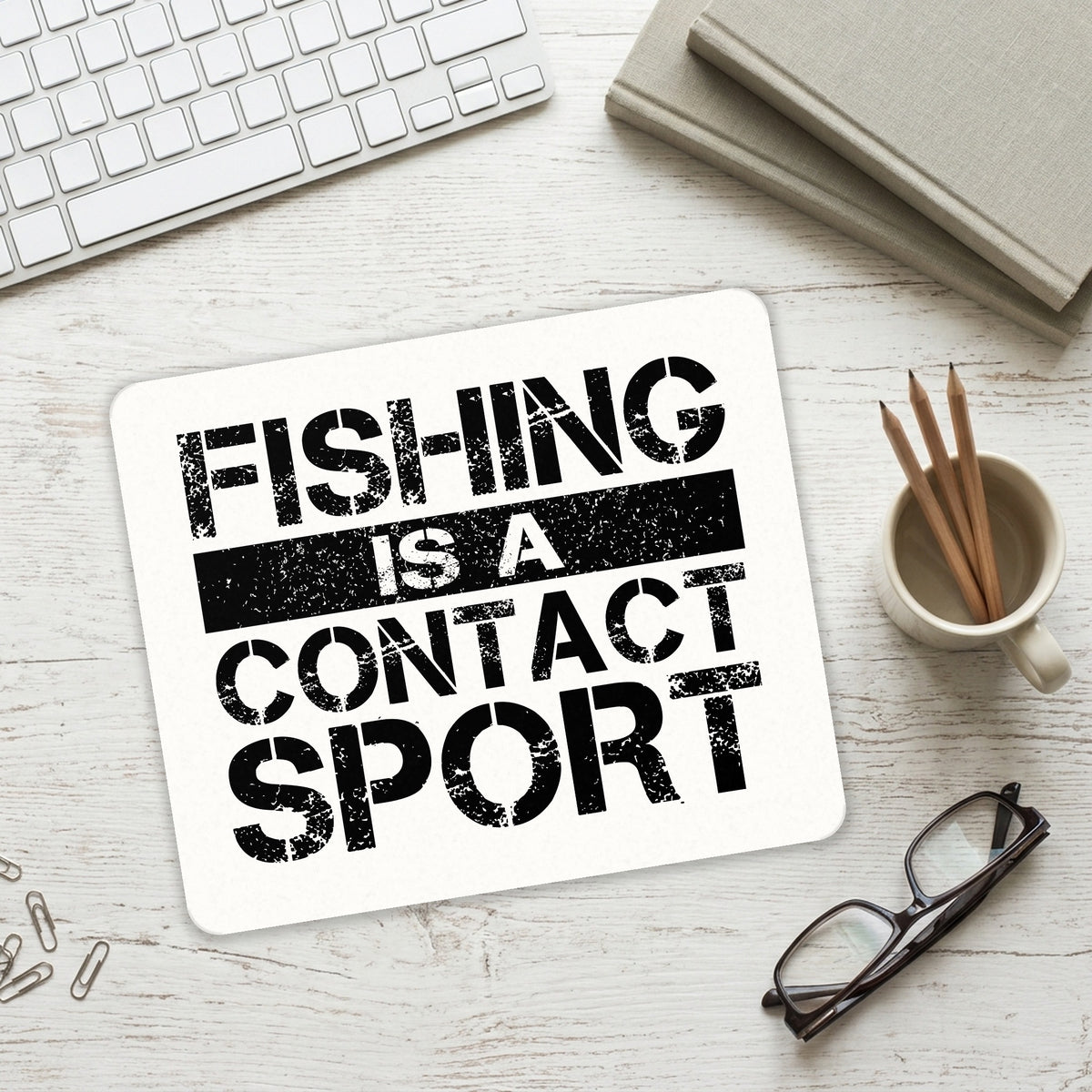Fishing is a Contact Sport mouse pad on a desk with a keyboard