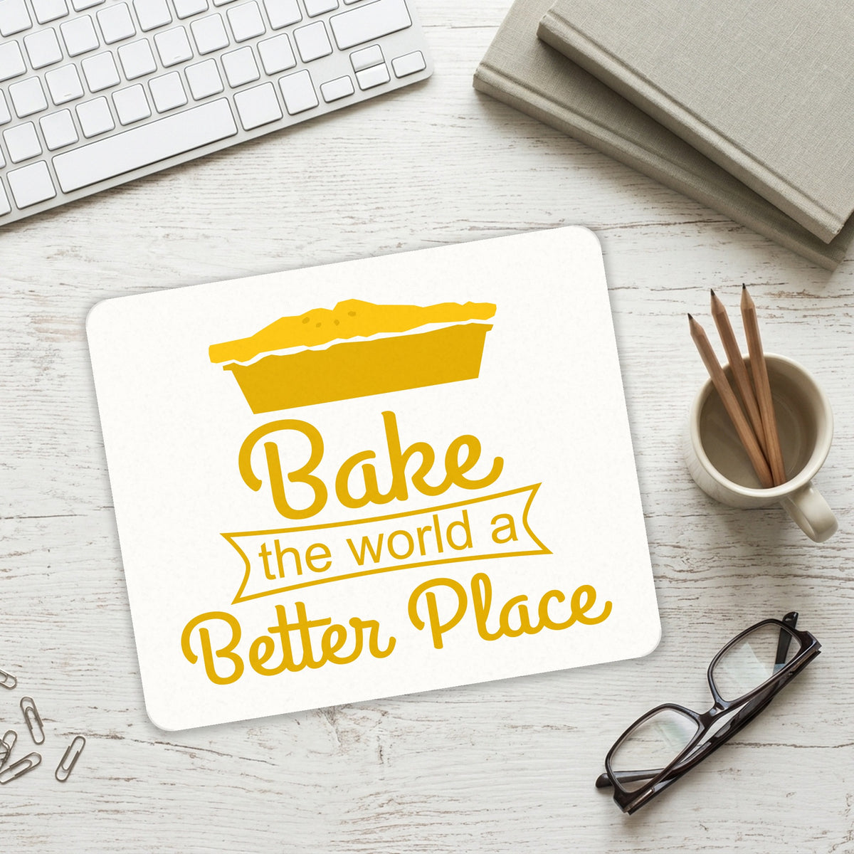 Bake the World a Better Place mouse pad on a desk with a keyboard