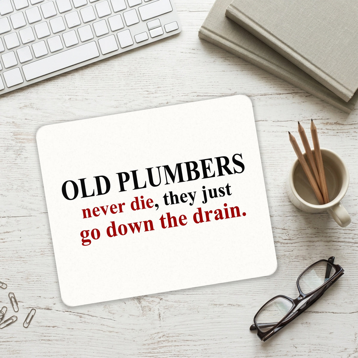 Old Plumbers Never Die - Down the Drain mouse pad on a desk with a keyboard