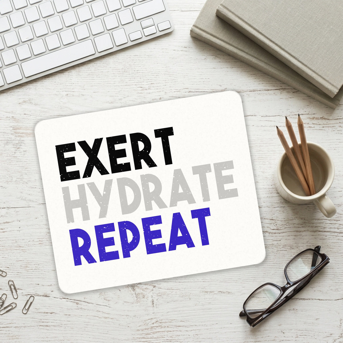 Exert Hydrate Repeat mouse pad on a desk with a keyboard