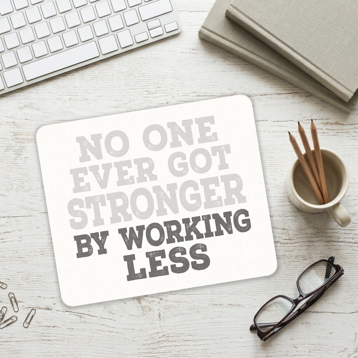 No One Ever Got Stronger Working Less mouse pad on a desk with a keyboard