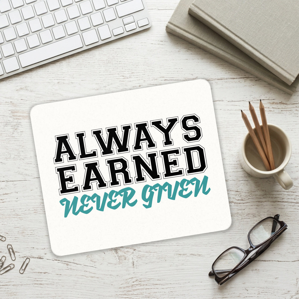 Always Earned Never Given mouse pad on a desk with a keyboard
