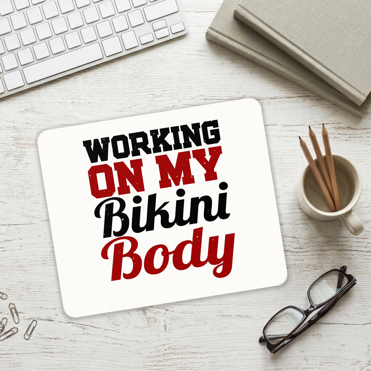 Working On My Bikini Body mouse pad on a desk with a keyboard