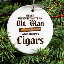 DistinctInk® Hanging Ceramic Christmas Tree Ornament with Gold String - Great Gift / Present - 2 3/4 inch Diameter - Never Underestimate Old Man Who Smokes Cigars